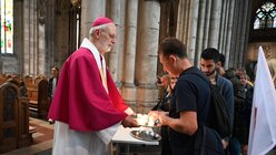 Weihbischof Ansgar Puff verteilt an jeden Andachtteilnehmer eine Kerze. / © Beatrice Tomasetti (DR)