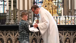 Jedem Kommunionkind überreicht Schulseelsorger Hofer bei der Tauferinnerungsfeier seine selbstgebastelte Kerze / © Beatrice Tomasetti (DR)