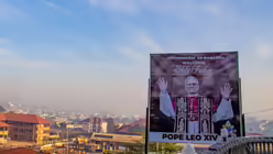 Eine Reklametafel am Stra&szlig;enrand begr&uuml;&szlig;t den Heiligen Vater Papst Leo XIV. in Bamenda, Kamerun. / &copy; Welba Yamo Pascal/AP (dpa)