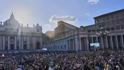Menschen verfolgen auf dem Petersplatz auf einer Videoleinwand, wie weißer Rauch aus dem Schornstein der Sixtinischen Kapelle aufsteigt / © Bernat Armangue (dpa)