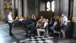 Eine Reisegruppe sitzt in der Grafenkapelle im Neuwünster in Würzburg / © Oliver Kelch (DR)