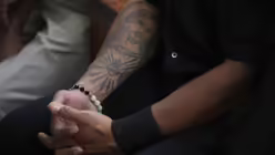 Mann in Osttimor mit einem auf den Arm tätowierten Abbild von Jesus Christus nimmt an einer Sonntagsmesse teil / © Dita Alangkara (dpa)