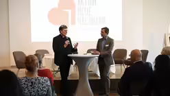 Kardinal Woelki berichtet im Gespräch mit Moderator Alexander Königsmann von den Anfängen der Aktion Neue Nachbarn. / © Beatrice Tomasetti (DR)