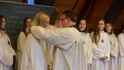 Jedem M&auml;dchen legt Chorleiter Sperling die von Egino Weinert geschaffene Plakette um / &copy; Beatrice Tomasetti (DR)