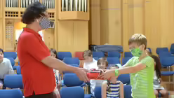 Julius überreicht dem beliebten Pädagogen, der nun in den Ruhestand geht, im Namen der Klasse ein Abschiedsgeschenk / © Beatrice Tomasetti (DR)