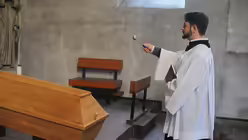 Kursteilnehmer Dr. Dominik Matuschek segnet den Sarg. / © Tomasetti (DR)