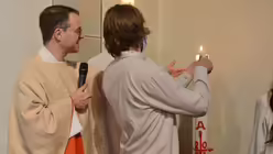 Marc Isaak entzündet seine Taufkerze an der Osterkerze. / © Beatrice Tomasetti (DR)