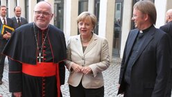 Kardinal Marx, Angela Merkel und Prälat Jüsten (KNA)