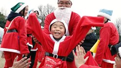 Menschen und Kinder laufen im roten Kostüm als Weihnachtsmann beim Tokyo Great Santa Charity-Lauf mit. / © kyodo (dpa)