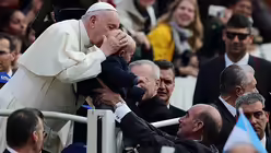 Papst Franziskus k&uuml;sst den Kopf eines kleinen Kindes, das ihm bei seiner w&ouml;chentlichen Generalaudienz entgegen gestreckt wird. / &copy; Evandro Inetti/ZUMA Wire (dpa)