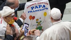 Papst Franziskus (r) erhält am Ende seiner wöchentlichen Generalaudienz in der Halle Paul VI. im Vatikan ein T-Shirt mit seinem Namen von Mitgliedern der "Clown Doctors" / © Gregorio Borgia (dpa)