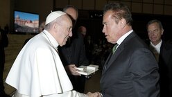 Papst Franziskus begrüßt Arnold Schwarzenegger (r.) / © Osservatore Romano (KNA)