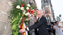 Peter Tschentscher (SPD), Erster Bürgermeister von Hamburg, richtet die Schleife eines Kranzes an den Ruinen der St. Nikolai-Kirche / © Daniel Reinhardt (dpa)