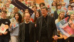 Pirmin Spiegel und Erzbischof Woelki posieren für ein gemeinsames Gruppenbild mit den Schülern im Foyer der Philharmonie. / © Tomasetti (DR)