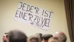 Plakat mit der Aufschrift "Jede*r ist eine*r zu viel #3677" bei der Aktion "Steh auf und geh! - Br&uuml;ckenbau zum Wandel in der katholischen Kirche jetzt" / &copy; Julia Steinbrecht (KNA)