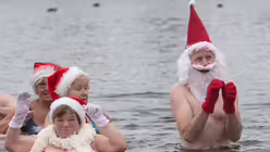 Verkleidete Teilnehmer am Weihnachts-Baden im Orankesee des Vereins "Berliner Seehunde" vergnügen sich im kalten Wasser / © Paul Zinken (dpa)