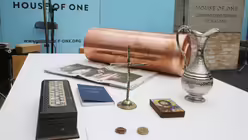 Verschiedenen Gegenst&auml;nde f&uuml;r Dokumentenh&uuml;lse liegen bei der Grundsteinlegung f&uuml;r das Mehrreligionengeb&auml;ude "House of One" in Berlin auf dem Tisch / &copy; Wolfgang Kumm (dpa)