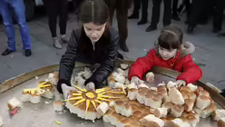 Zwei M&auml;dchen zerbrechen in Belgrad das traditionelle Weihnachtsbrot / &copy; Darko Vojinovic (dpa)